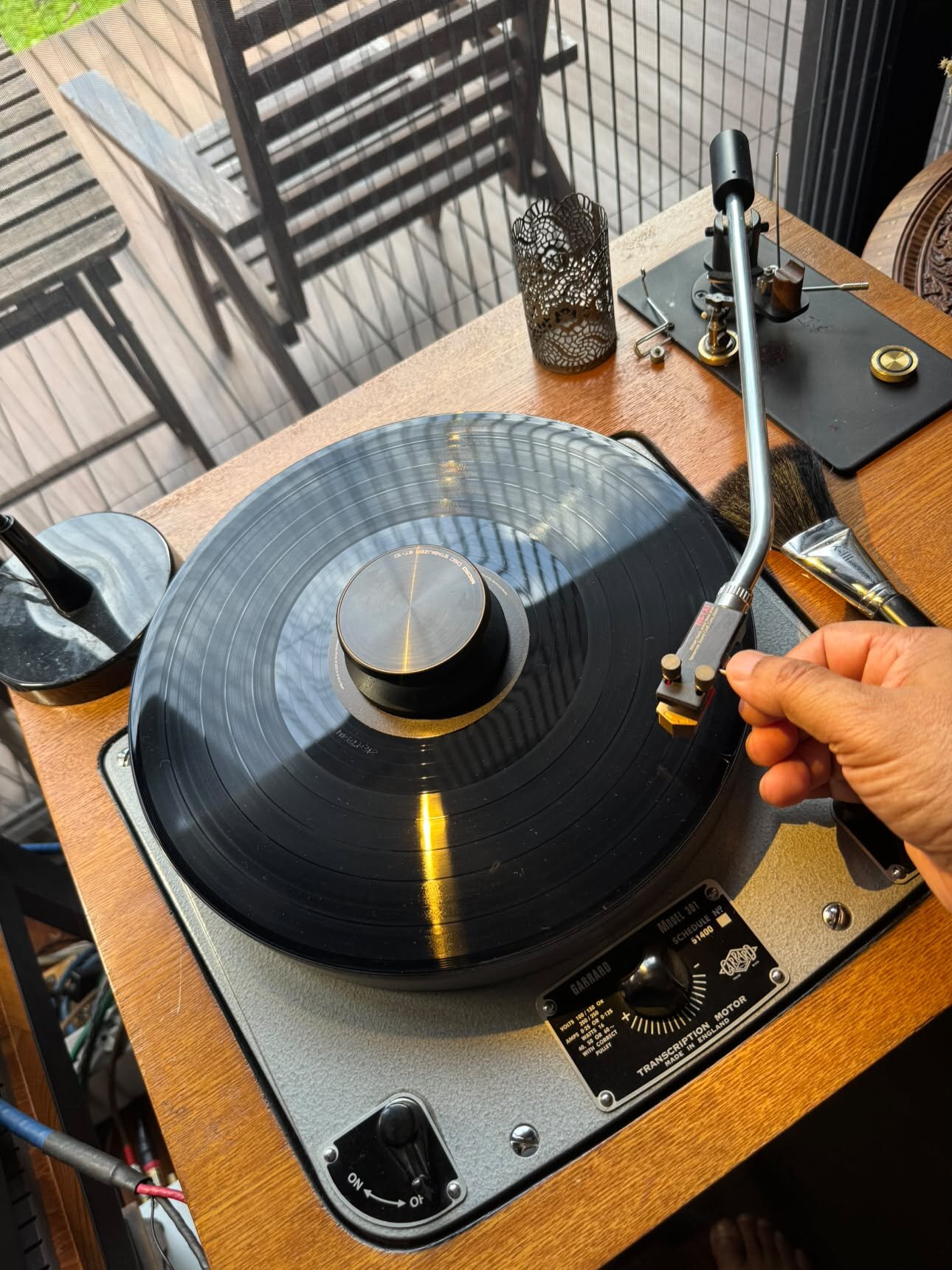 Main posant le bras de lecture sur un disque, platine Garrard 301