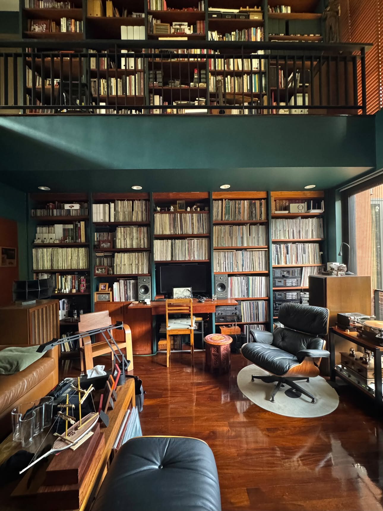 Vue plongeante sur la pièce depuis la mezzanine, murs de disques sur deux étages, fauteuil Eames