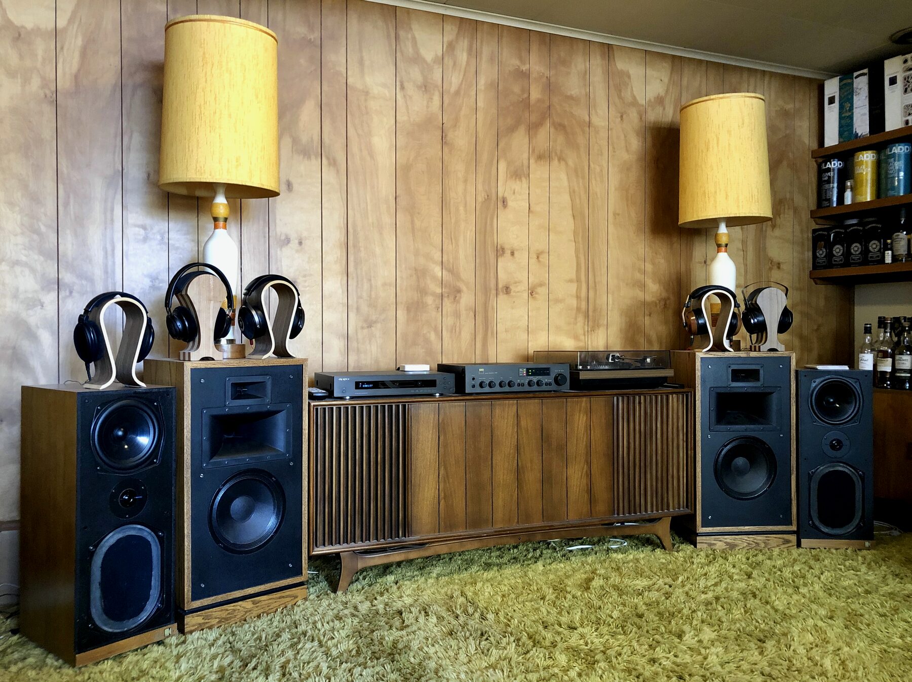 Deux paires de casques audio posées sur des socles en bois, ampli Macintosh, platine visible en fond