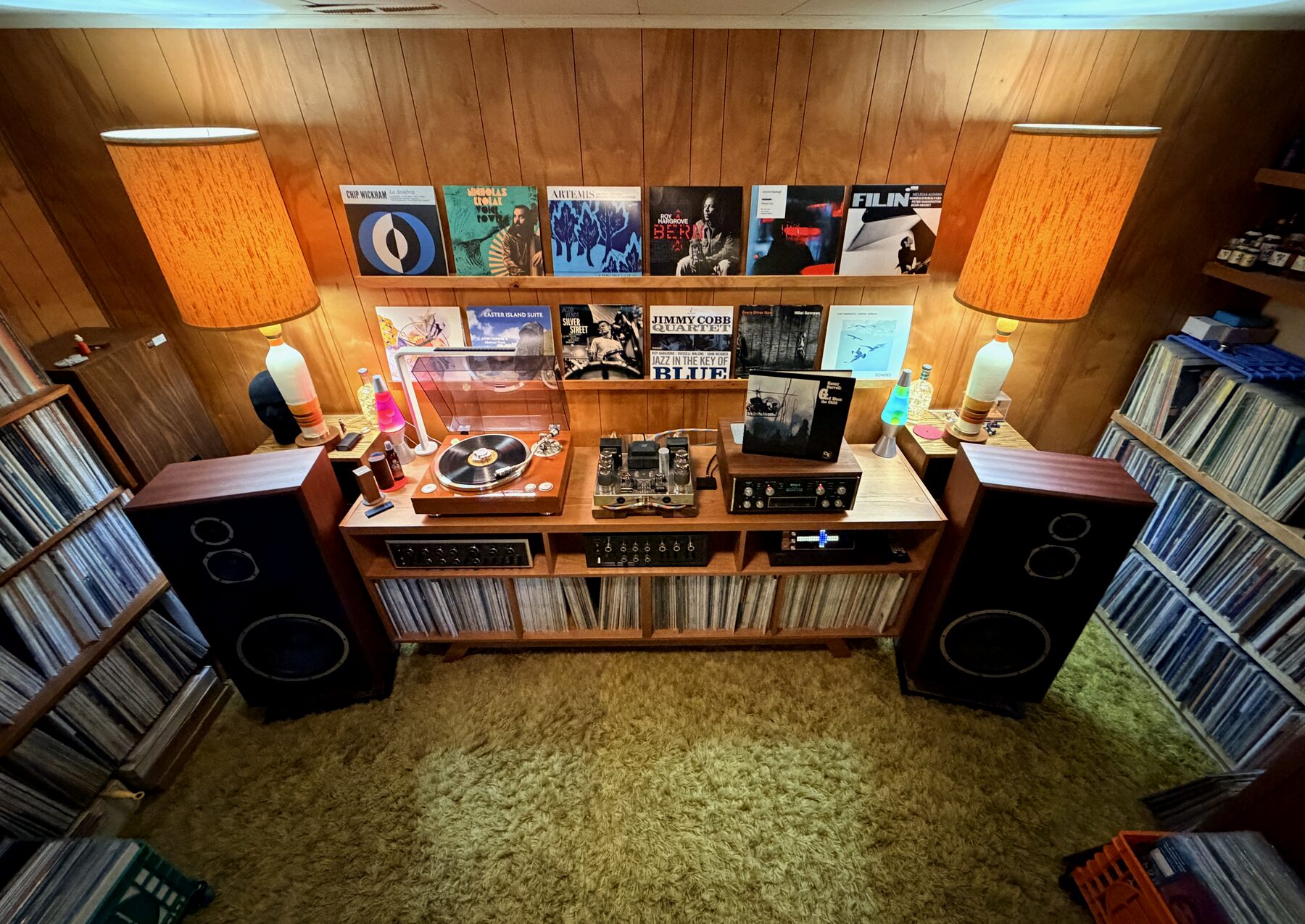 Vue en plongée sur le meuble hi-fi complet, disques japonais affichés, platine sous capot, tapis shag vert au sol