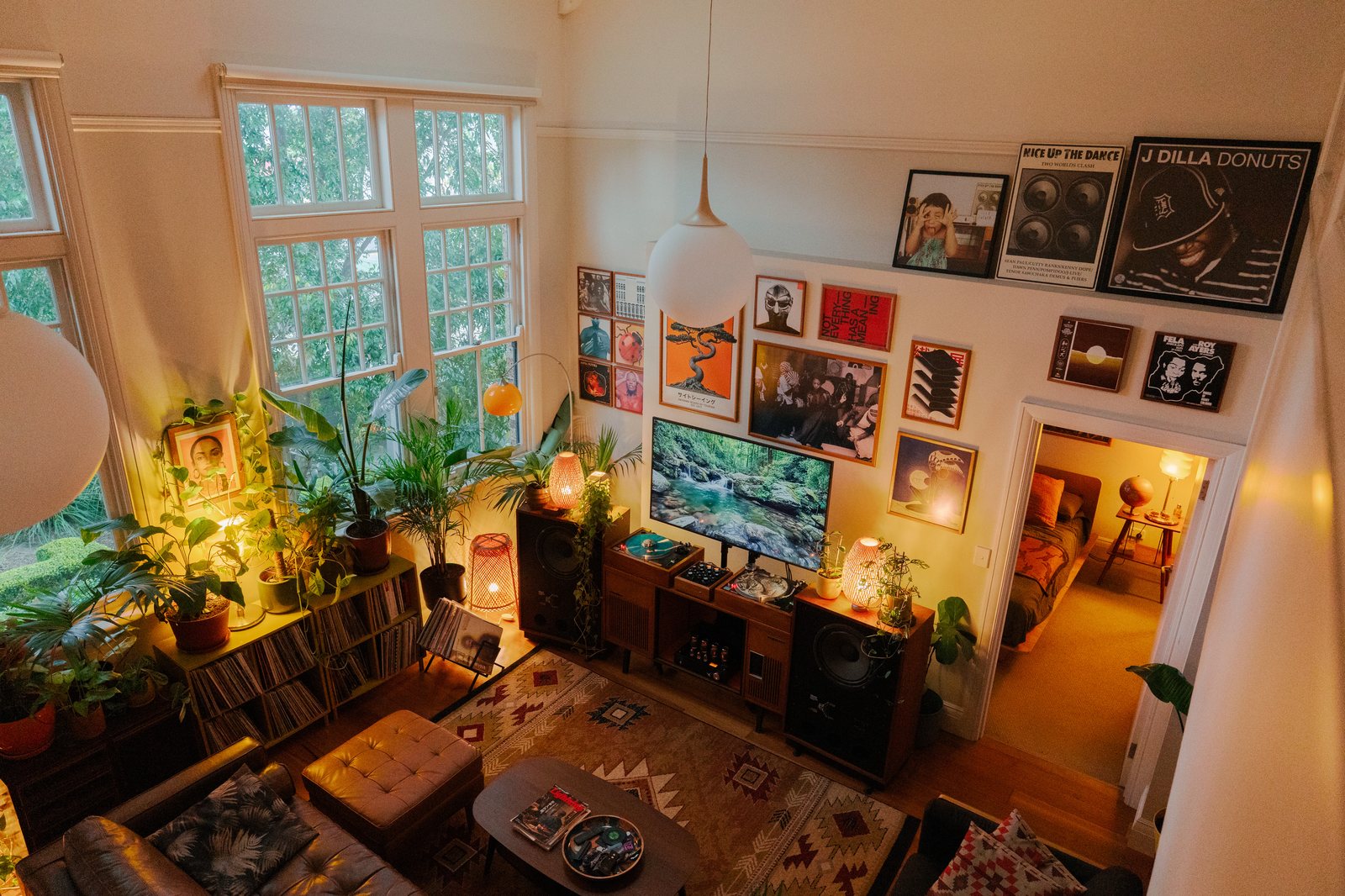Vue en plongée sur le salon, plantes, bibliothèque de vinyles et mur de pochettes encadrées