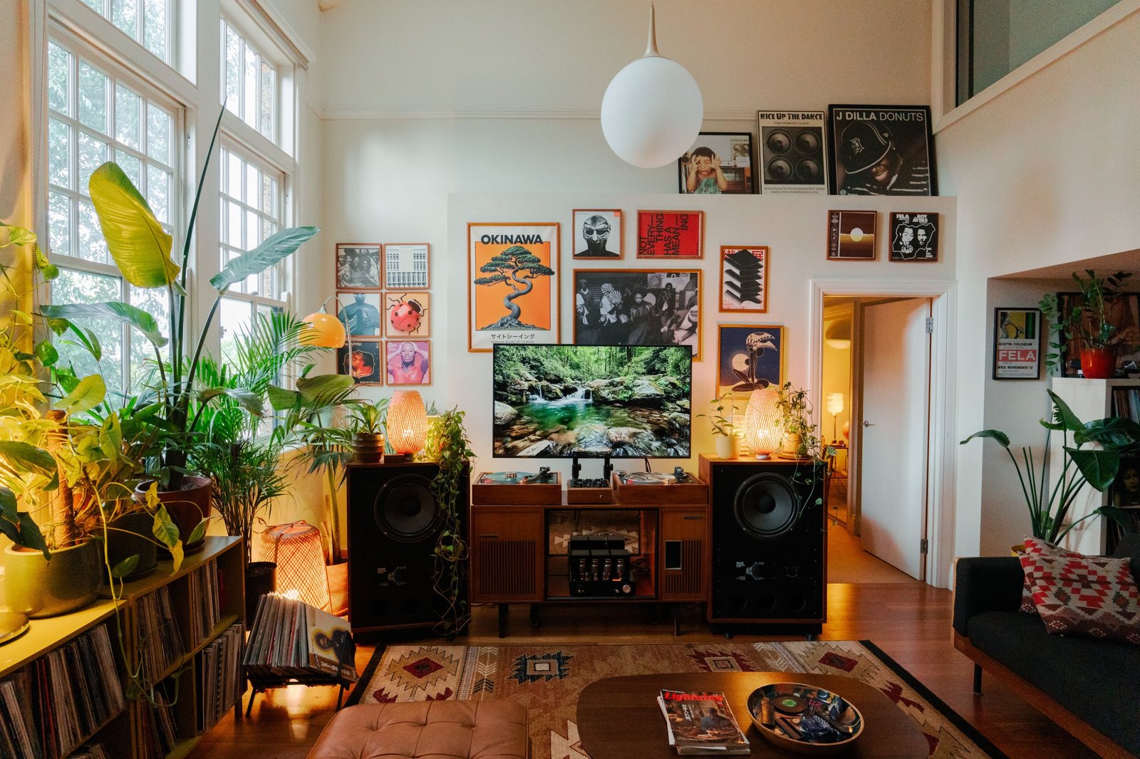 Mur de pochettes et affiches encadrées, téléviseur et platines, plantes de part et d’autre