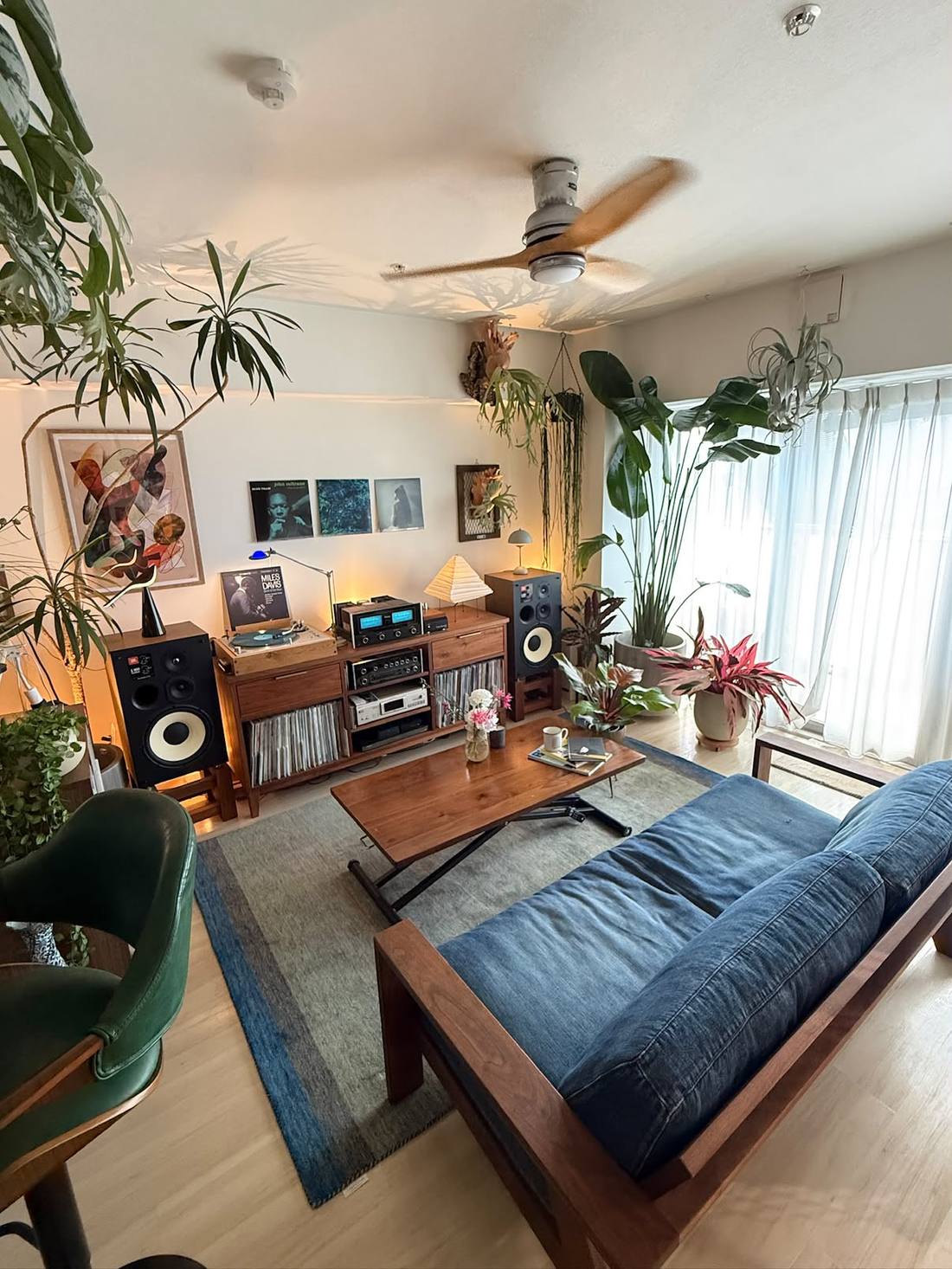 Vue large du salon, mur de plantes, bibliothèque en noyer entre les enceintes JBL